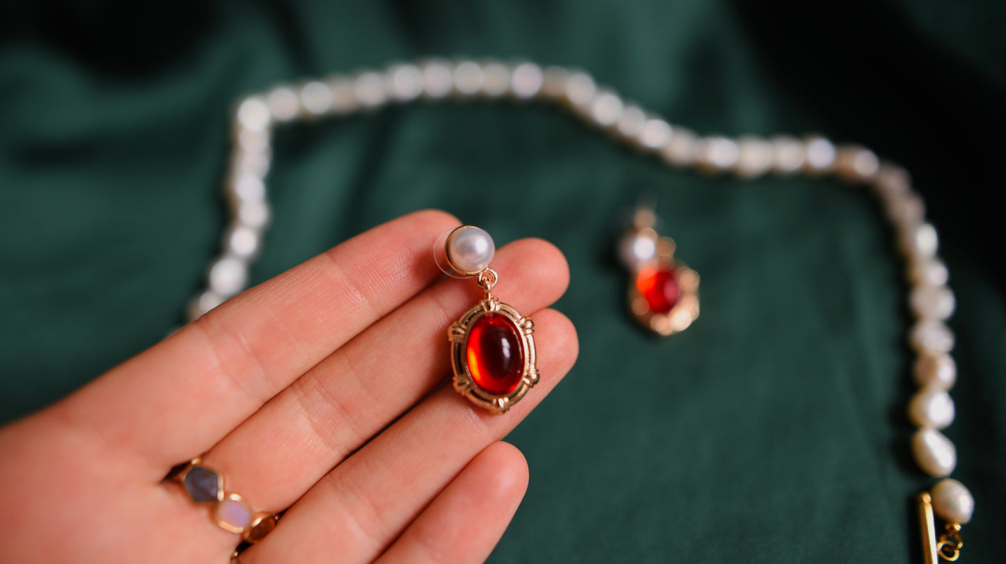 Goldene Ohrringe mit rotem Akzent und Perle